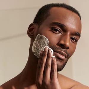 Homem aplicando produto de skincare no rosto.